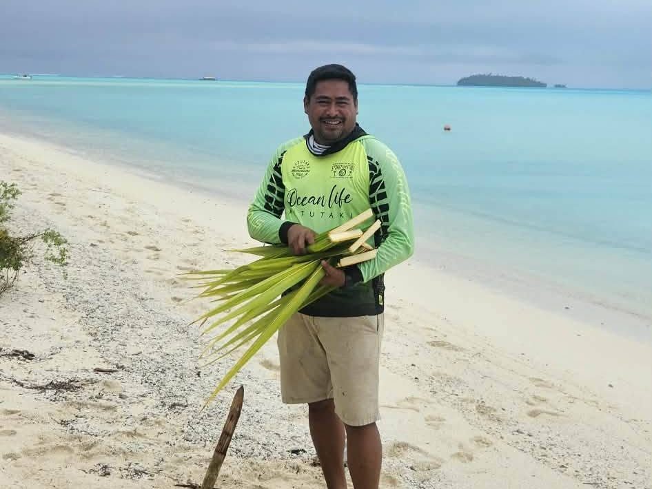 One of our crew on the sand with freshly cut coconut fronds for weaving